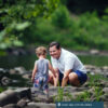 A father and child play in the creek together.