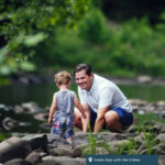 A father and child play in the creek together.
