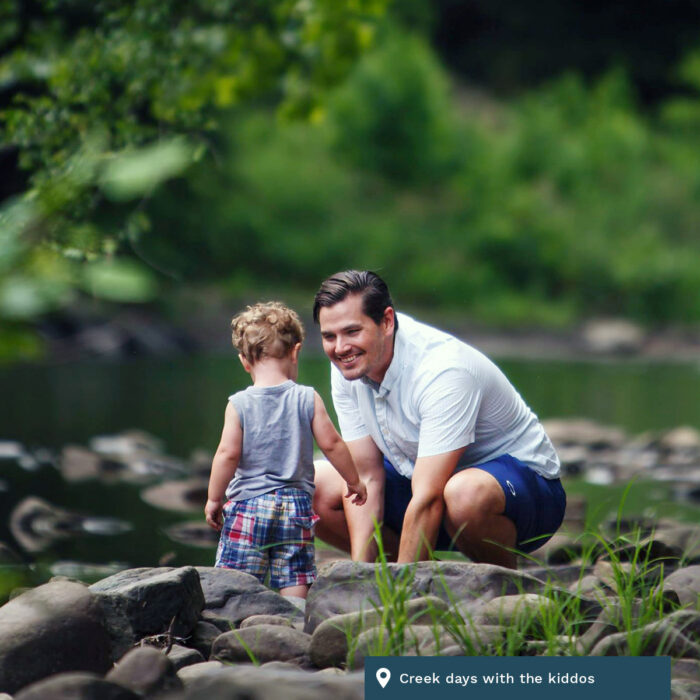 A father and child play in the creek together.