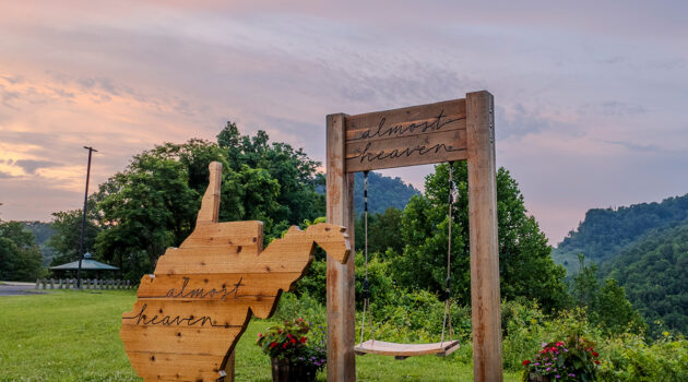 An Almost Heaven swing and sign sits at Chief Logan State Park at sunset.