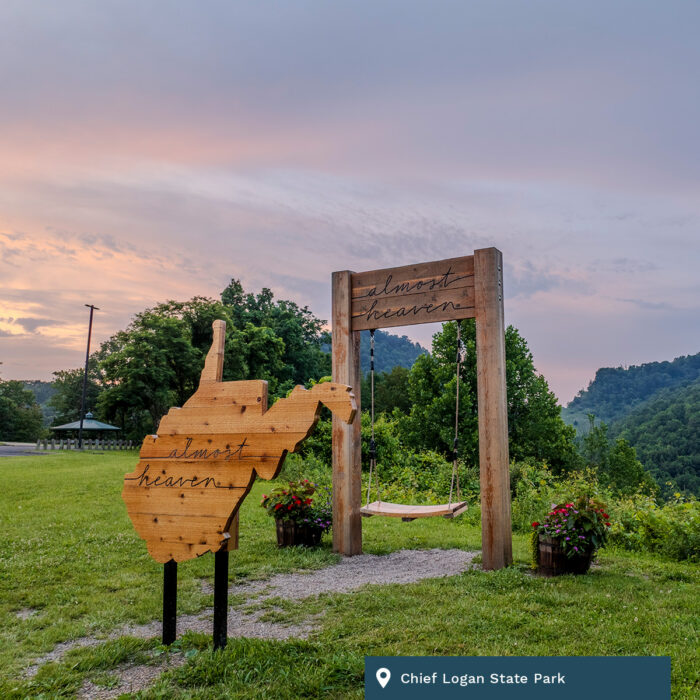 An Almost Heaven swing and sign sits at Chief Logan State Park at sunset.